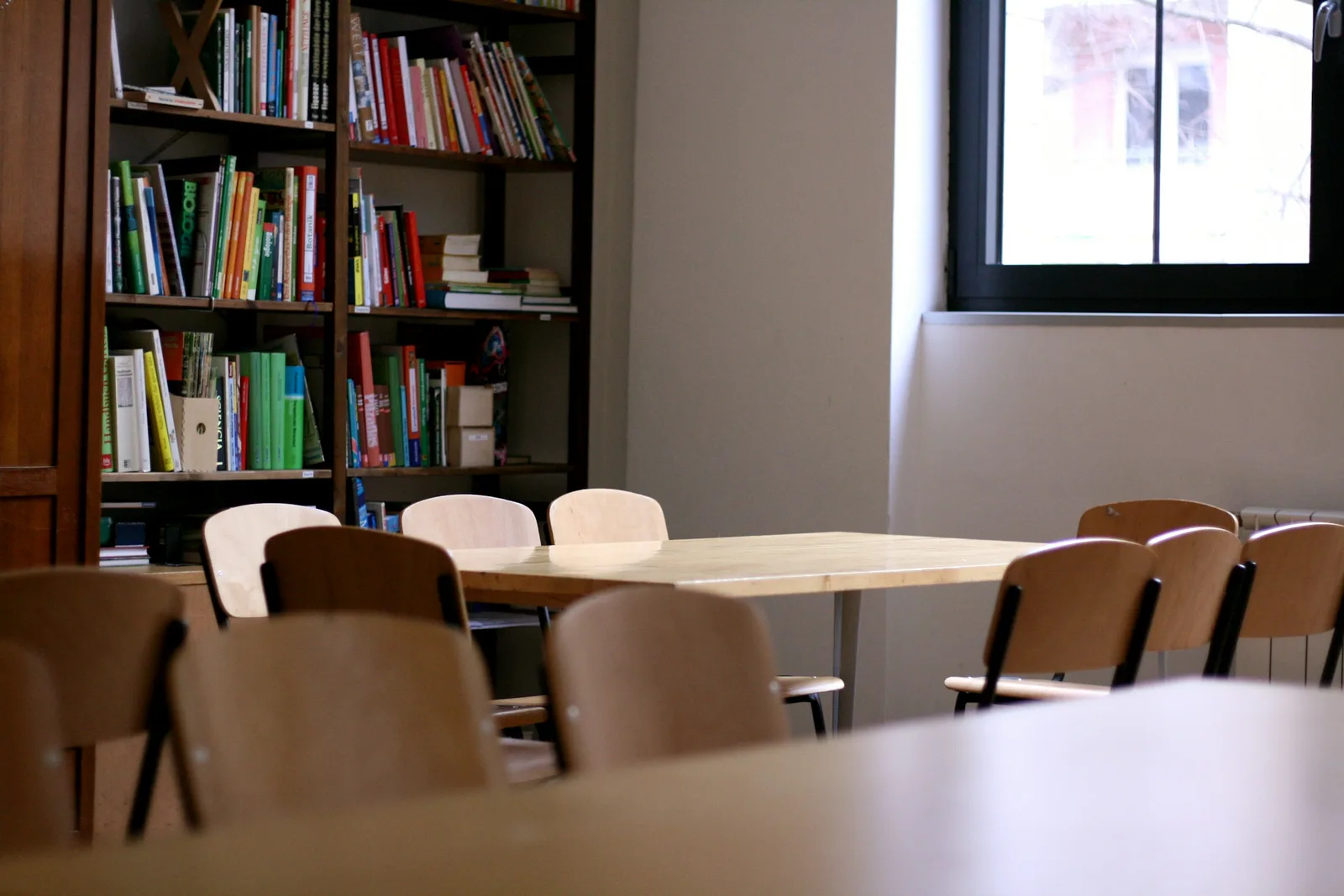 A quiet meeting room with chairs around a wooden table, soft natural light from a window