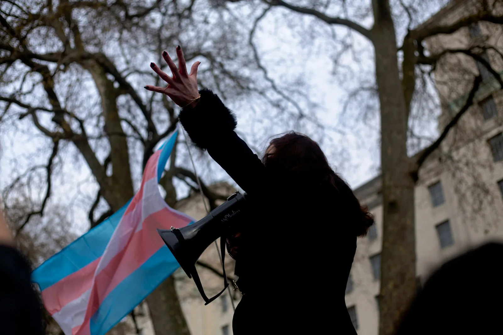 A community member raising a hand in front of a trans flag at a march