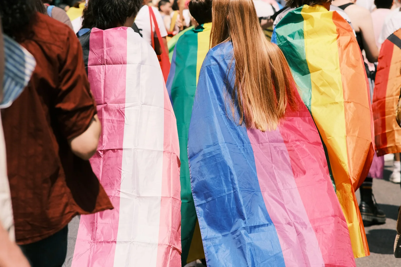 A group of community members wrapped in trans and pride flags at a gathering